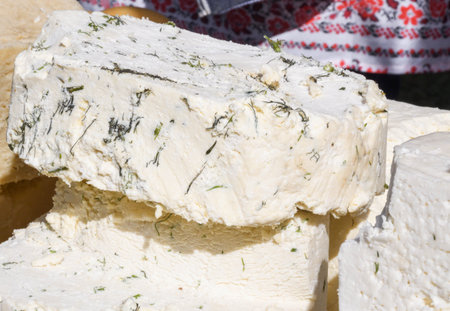 A sliced piece of cheese with dill and spices, for sale on counter top, during food festival....
