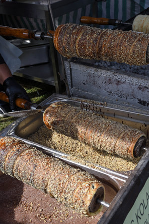 Kurtos kalacs or chimney cakes, preparing cooking on charcoal grill, street food traditional...