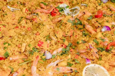 Fresh seafood rice risotto cooking steaming in large wok pan during hotel brunch buffet outside outdoor in the garden by the pool. Fresh Food Buffet Brunch Catering Dining Eating Party Sharing Conceptの写真素材