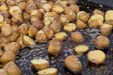 Potato wedges in skin roasting frying in large pan during hotel brunch buffet outside outdoor in the garden by the pool. Fresh Food Buffet Brunch Catering Dining Eating Party Sharing Concept.の写真素材