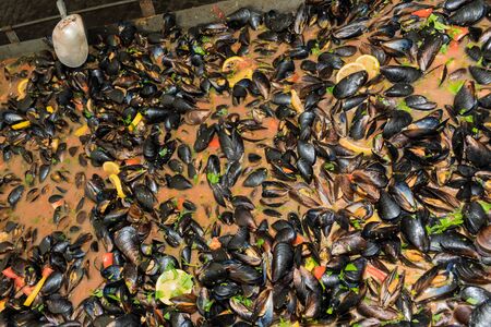 Fresh mussels at grill pan. Seafood barbecue outdoors. Picnic healthy food, mussels in shells.Plenty of mussel shells cooking at large metallic pan. Brunch Catering Dining Eating Party Sharing Conceptの写真素材