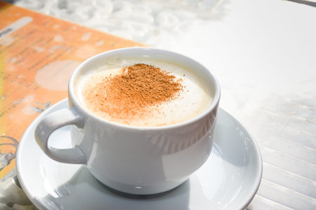 white cup of salep milky hot drink of Turkey with cinnamon powder and sticks healthy spice and...