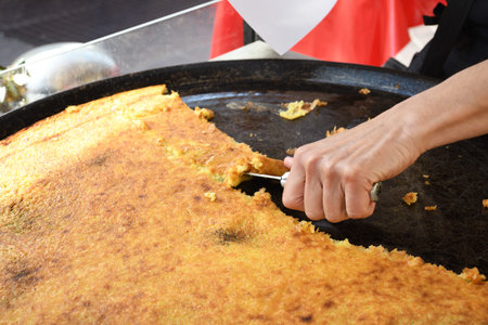 Nice, France, 25th of February 2020: big Plate of Farinata or Cecina or Torta di ceci thin unleavened pancake or crepe of chickpea flour originating in Genoa cooked in a wood oven, socca for saleの写真素材