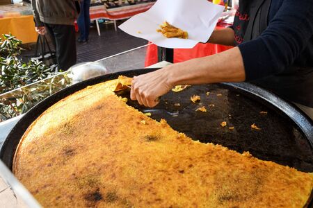 Nice, France, 25th of February 2020: big Plate of Farinata or Cecina or Torta di ceci thin unleavened pancake or crepe of chickpea flour originating in Genoa cooked in a wood oven, socca for saleの写真素材