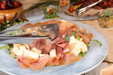 Meat and cheese cuts platter during outdoor brunch buffet in the garden or terrace restaurant. Food...