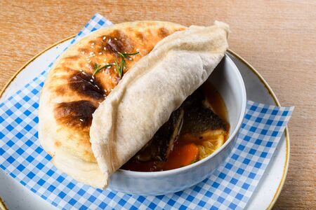 Fish stew in a white bowl, served with a pita bread cover on top. Levantine East Mediterranean foodの写真素材