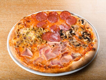 Pizza quattro stagioni is a variety of pizza in Italian cuisine that is prepared in four sections with diverse ingredients, with each section representing one season of the year.の写真素材