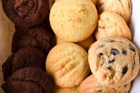 Homemade vanilla, orange, lemon chocolate chip cookies biscuits stack on a white plate ready to be served in a restaurant setting, bakery or pastry shopの写真素材
