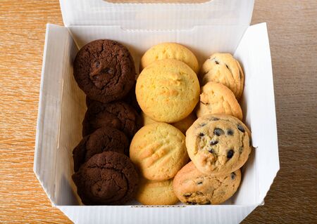 Homemade vanilla, orange, lemon chocolate chip cookies biscuits stack on a white plate ready to be served in a restaurant setting, bakery or pastry shopの写真素材