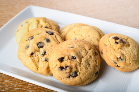 Homemade vanilla, orange, lemon chocolate chip cookies biscuits stack on a white plate ready to be...