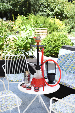 Shisha hookah on restaurant table in the garden. Metal hookah on a summer terrace with a blurred background.の写真素材