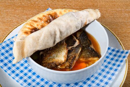 Fish stew in a white bowl, served with a pita bread cover on top. Levantine East Mediterranean foodの写真素材