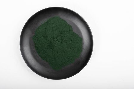 An isolated tablespoon of dried organic spirulina algae powder, on white or rustic background. Healthy living, detox recipes, raw vegan smoothie or juice ingredientsの写真素材