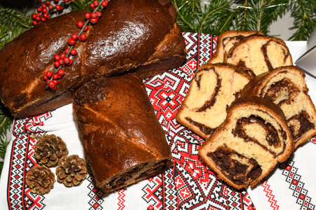 Closeup of slices of homemade traditional Romanian sweet bread named "cozonac", with cacao, raisins, various nuts and chocolate chips, ready to be eaten. Eastern European freshly baked dessert.の写真素材