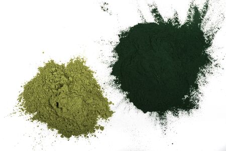 An isolated tablespoon of dried organic wheat grass and spirulina powder, on white or rustic background. Healthy living, detox recipes, raw vegan smoothie or juice ingredientsの写真素材