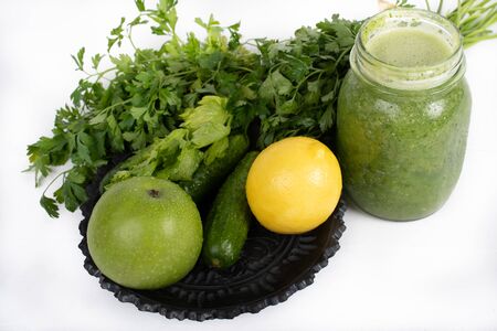 Jar of raw green vegetable smoothie juice with lemon, cucumbers, apple, apio and parsley, on white backgroundの写真素材