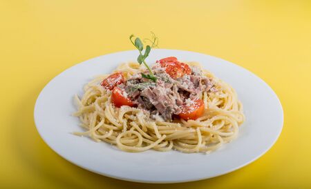 Spaghetti cooked pasta with ingredients on a yellow background. Colorful top and closeup view of bowl of traditional Italian dish. Flat lay design concept with copy space for promotionの写真素材