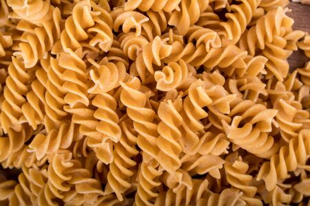 Gluten-free penne pasta from chickpeas, red lentils on wooden cutting board. basil,tomatoes and garlic. shot from above and closeup.food background italian penne and fusilliの写真素材