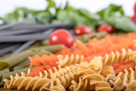 Assortment of different types of gluten-free penne pasta from chickpeas, red lentils, peas on wooden cutting board. basil,tomatoes and garlic. shot from above and closeup.food background italian penneの写真素材