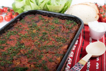 Traditional Romanian dish named "Varza a la Cluj" made from stewed cabbage, tomato paste and minced meat, rice and dill, red napkin, salad and tomatoes, bread and condimentsの写真素材