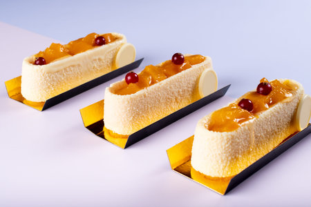 Mango and vanilla mousse bar tasty dessert isolated on pastel background with cranberry on top....