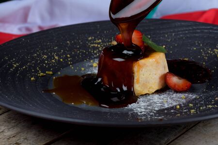 Rice pudding with caramel on top. Strawberries and black plate in a restaurant setting. Traditional Italian original recipe dessertの写真素材