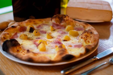 Hawaiian Pizza with pineapple, traditional italian oven baked dough with toppings: tomato sauce, cheese, mozzarella, ham. Simple brown wooden table restaurant settingの写真素材