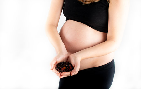 Pregnant woman holding tea leaves in her hands. Healthy eating diet lifestyle concept. Slim skinny pregnancy model posibg on white backgroundの写真素材