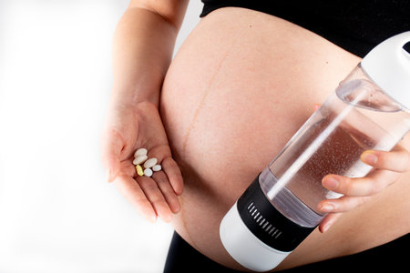 Pregnant woman taking prenatal vitamins and medicinal pills for healthy pregnancy. Folic acid, omega 3, vitamin d, medication for healthy baby development. belly abdomen skinny slim model isolatedの写真素材