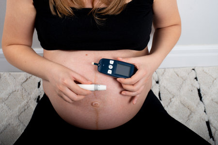 Pregnant woman verifing glycemic index with device for gestational diabetes in pregnancy. sugar free diet and healthy eating concept lifestyle for normal glycemic levelsの写真素材