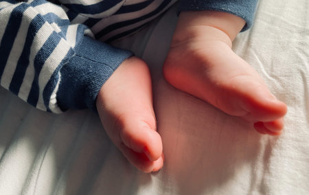 Small baby boy feet, no socks, little foot toes. Cute candid details closeup