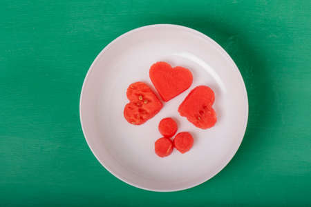 heart shapes and circles of watermelons on white platter, on green background, fun to eat fruit, kids on vacation. Refreshing and pretty to show love.の写真素材