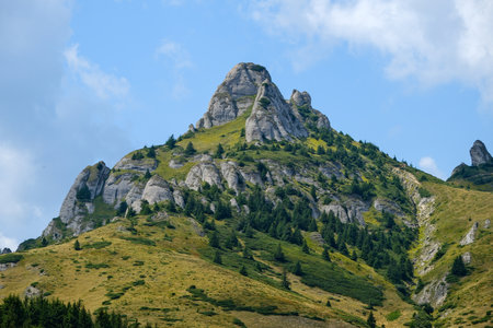 Steep rocky mountain with patches of vegetation under clear sky.の写真素材