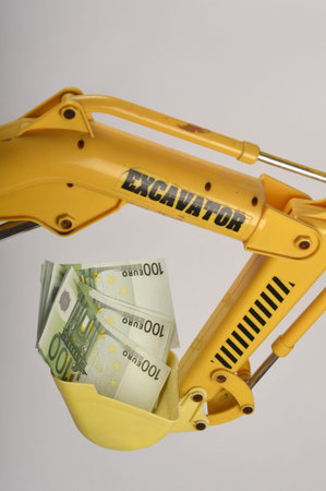 An excavator lifting up moneyの写真素材