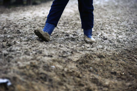 Man with rubber boots walking in the mudの写真素材