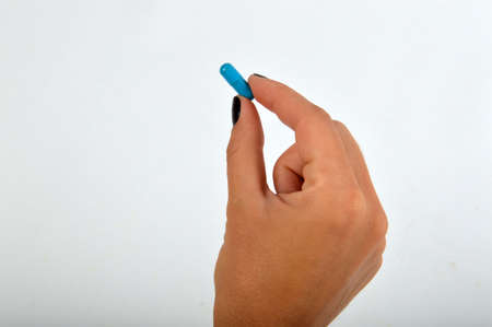 Woman holding between fingers a blue pillの写真素材