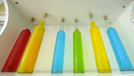Colored bottles arranged nicely on the shelfの写真素材