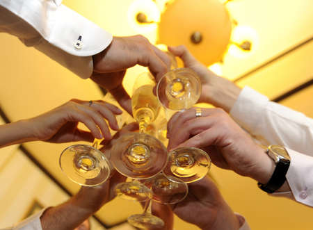 Friends holding glasses of white wine making a toastの写真素材