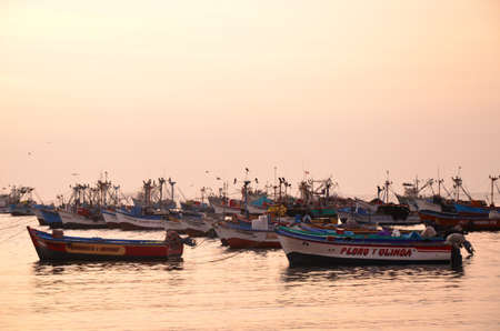 PARACAS, PERU- 11 JUNE, 2013: Old local fishing boats with fishing nets and seagulls anchored in the harbourのeditorial素材
