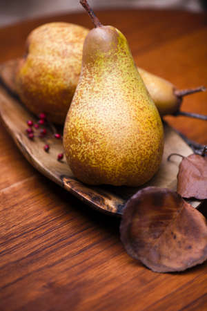 Two pears on a wooden plate with brown color wood background.の写真素材
