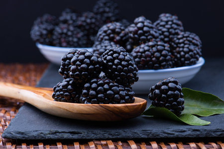 Blackberry on black stone board and wooden spoon, lots copyspaceの写真素材