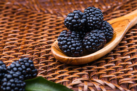 Blackberry on wicker background and wooden spoon, lots copyspaceの写真素材