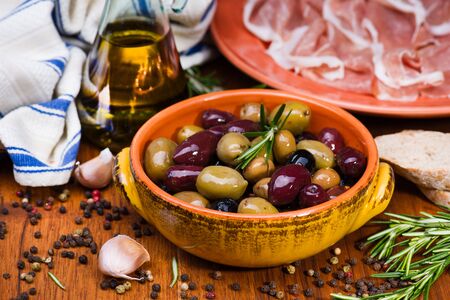 Olives in bow with prosciutto on wooden table and metal vintage spoonの写真素材