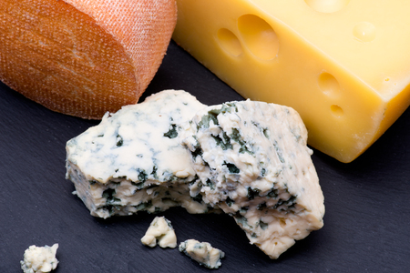 Cheeses on black background in assortment with other cheesesの写真素材