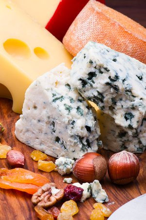 Cheeses with dried fruits and nuts on wooden boardの写真素材
