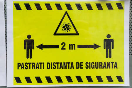 Bucharest, Romania - June 6, 2020: Poster indicating 2 meters social distancing is mandatory is displayed at the entry into a store, to mitigate the spread of the Coronavirus (COVID-19) outbreakのeditorial素材