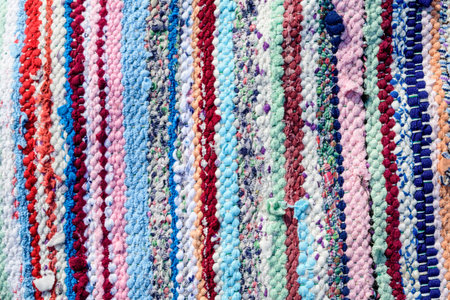 Background of manually woven textile materials of different colours, red, green, yellow, blue, green...