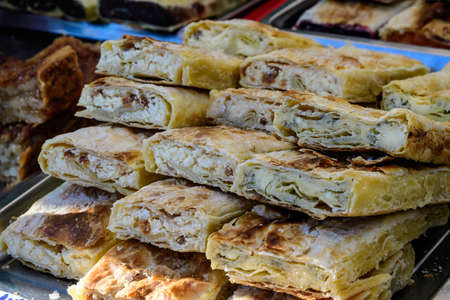 Fresh homemade cheese pie pieces displayed for sale at a street food market, side view of healthy food photograph with soft focusの写真素材