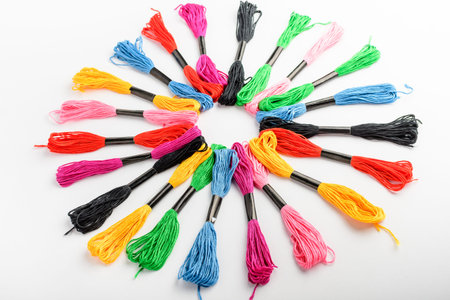 Many mixed vivid colored sewing threads for embroidery displayed in a circle isolated on a white...