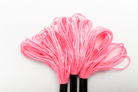 Three vivid pink sewing threads for embroidery isolated on a white table, top view or flat lay of...